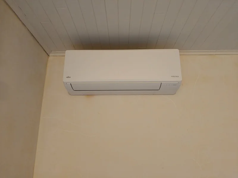 Witte Fujitsu-airco-binnenunit aan de muur onder een plafond