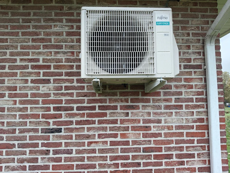 Fujitsu-airco-buitenunit op muurbeugels aan een bakstenen gevel