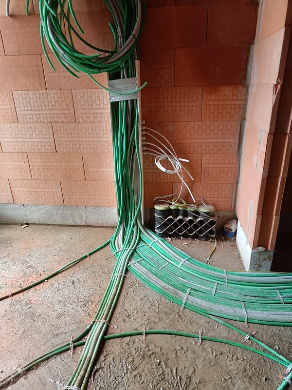 Gebundelde groene en grijze elektrische leidingen op de vloer en tegen de wand tijdens de ruwbouw