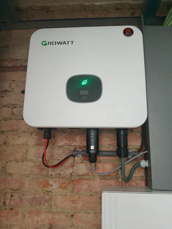 Growatt-omvormer aan een bakstenen muur met EWN-servicesticker