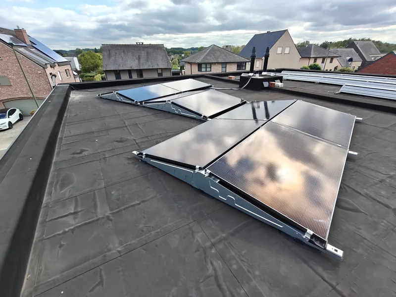 Zwarte zonnepanelen op een montagesysteem op een plat dak tussen woningen in Betekom