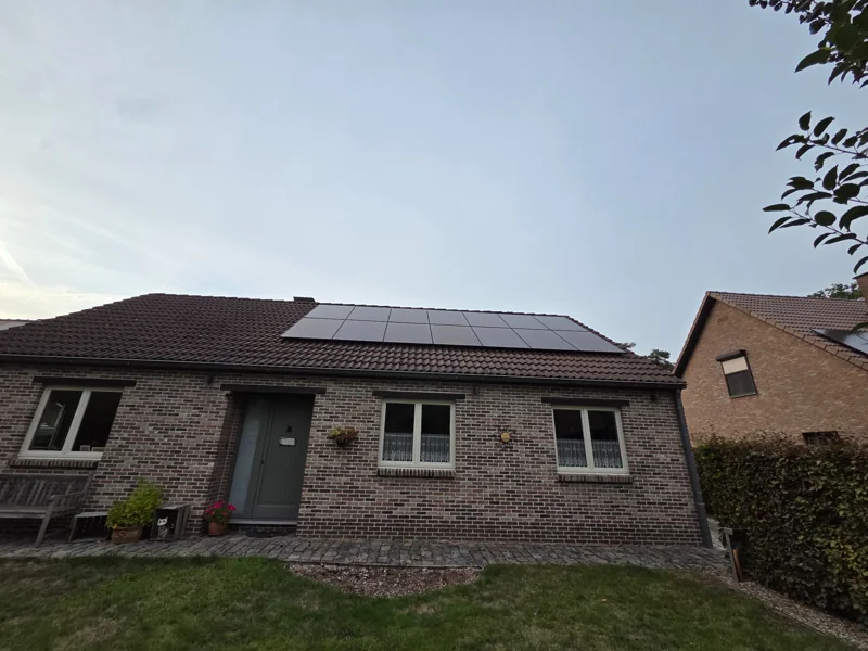 Zwarte zonnepanelen op het pannendak van een gelijkvloerse bakstenen woning in Putte