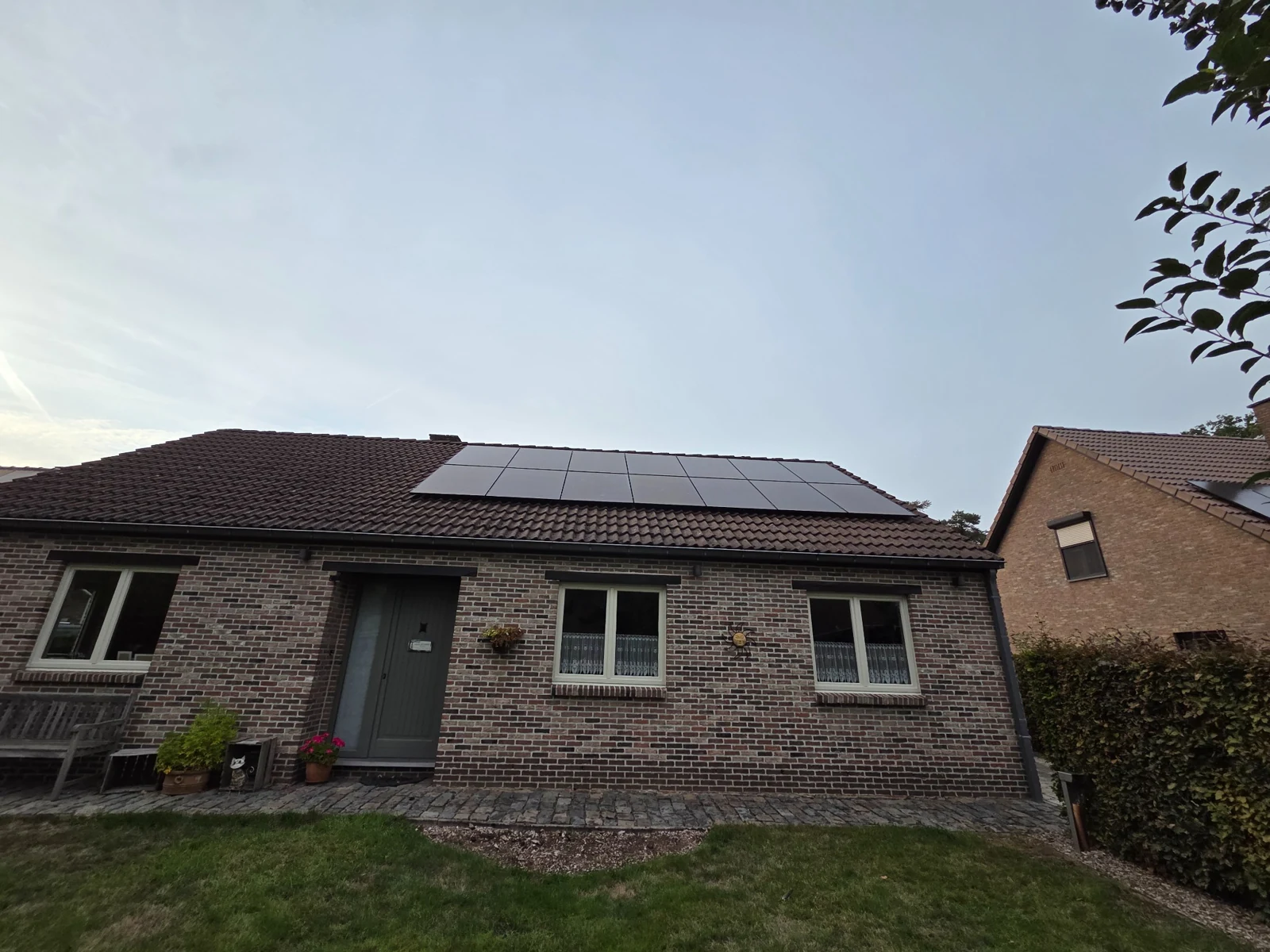 Zwarte zonnepanelen op het pannendak van een gelijkvloerse bakstenen woning in Putte