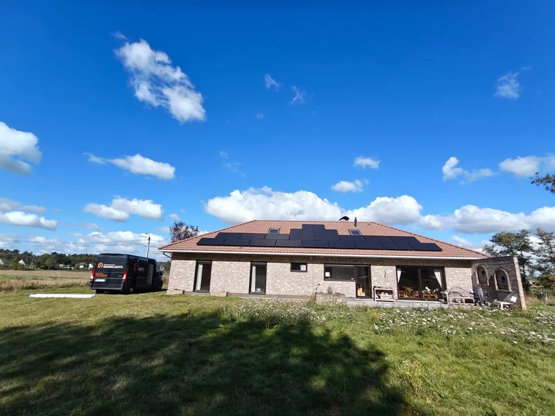 Woning in Itegem met zwarte zonnepanelen en een EWN Nauwelaerts-bestelwagen naast het huis