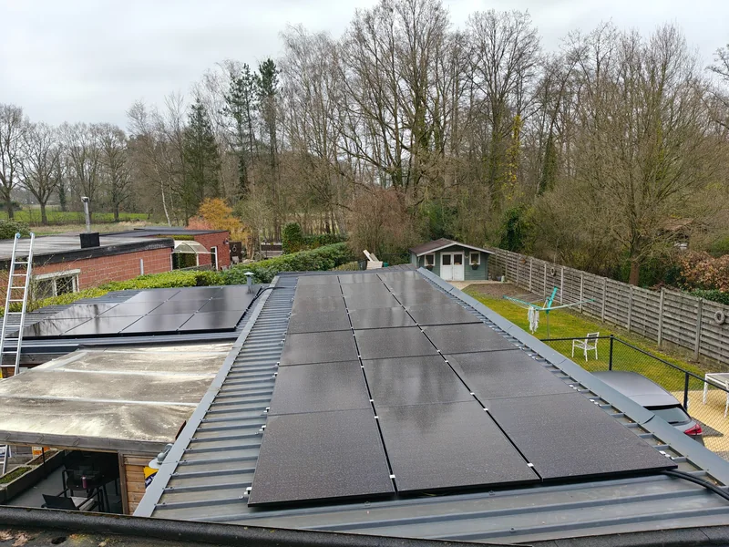 Zwarte zonnepanelen op een metalen dak met profielplaten bij een woning in Herenthout
