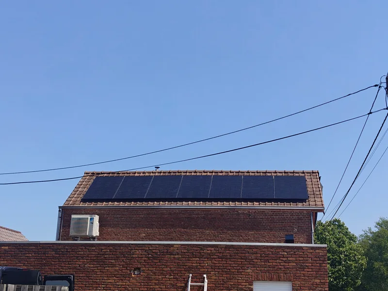 Een rij zwarte zonnepanelen op het pannendak van een bakstenen woning in Tremelo