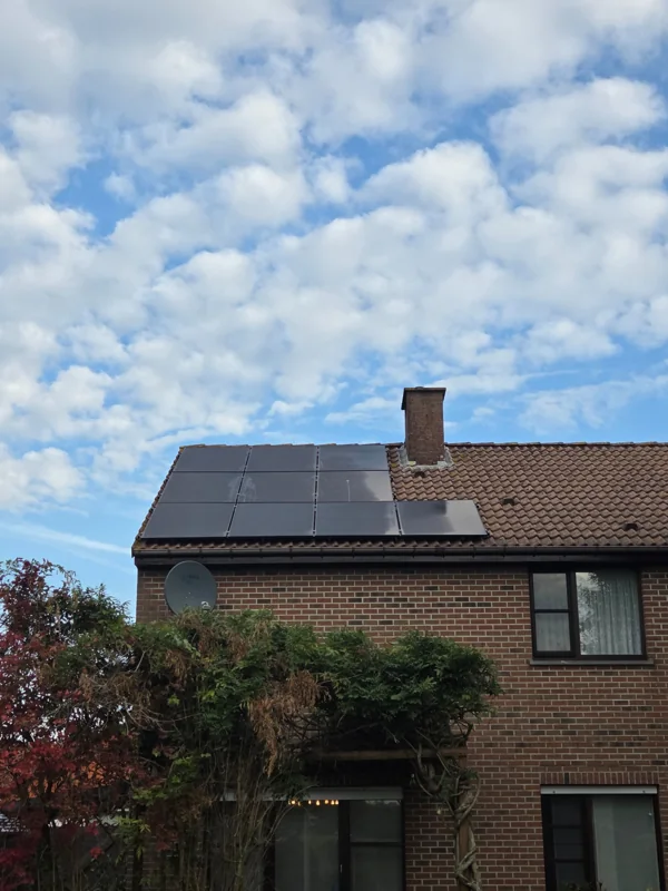 Zwarte zonnepanelen op het pannendak van een bakstenen woning in Heist-op-den-Berg, geplaatst door EWN
